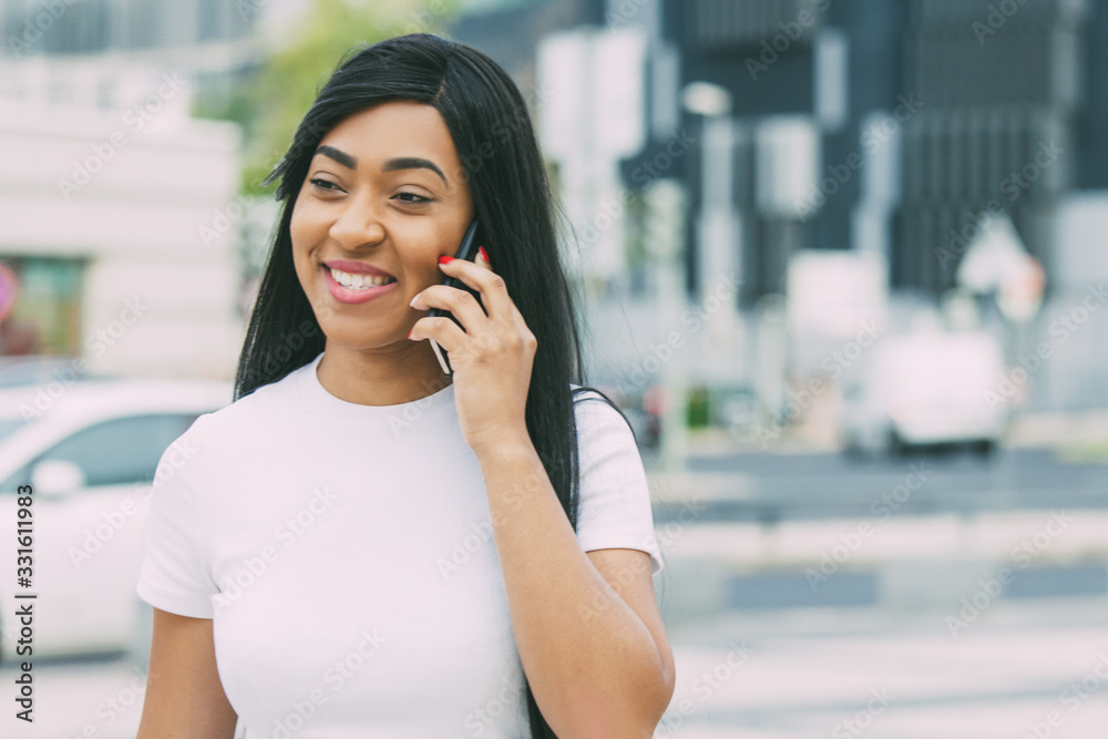 Beautiful smiling woman talking on smartphone. Cheerful attractive brunette talking to interlocutor through modern phone on street. Communication and technology concept Beautiful smiling woman talking on smartphone. Cheerful attractive brunette talking to interlocutor through modern phone on street. Communication and technology concept