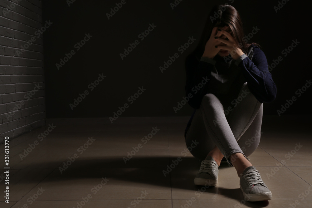 Depressed young woman on dark background