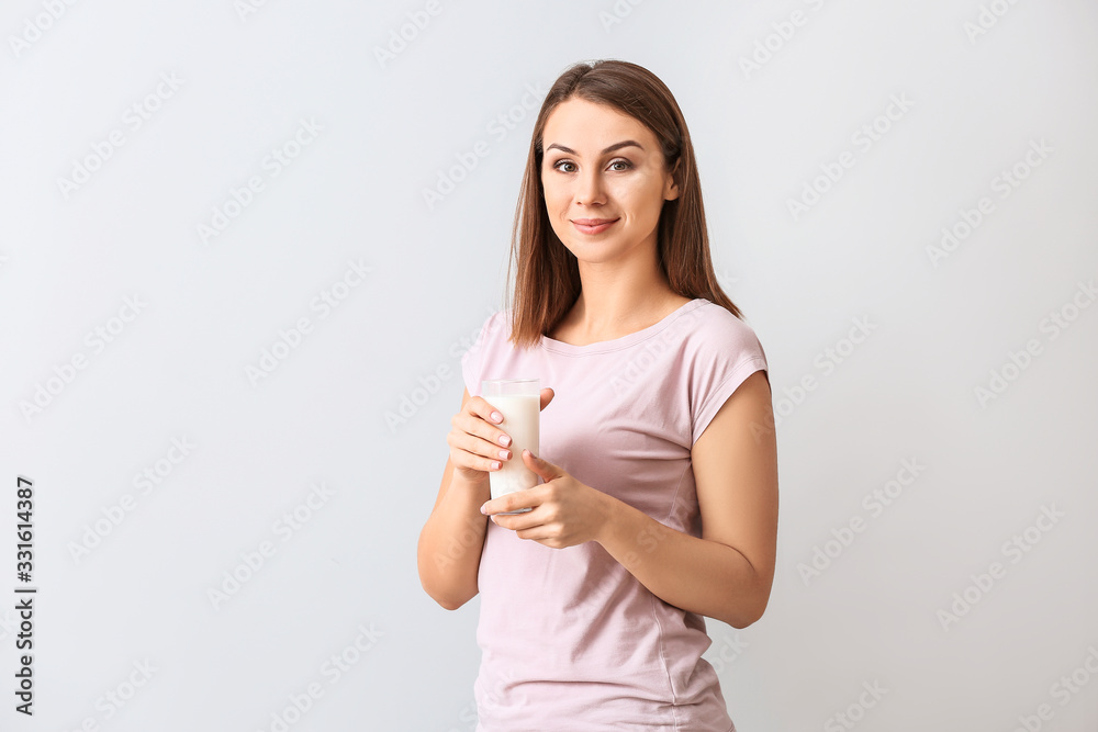 Beautiful young woman with glass of milk on light background Beautiful young woman with glass of milk on light background