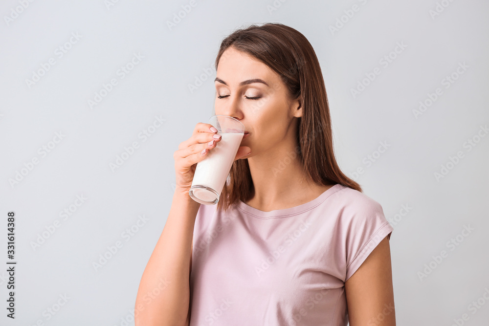 Beautiful young woman with glass of milk on light background Beautiful young woman with glass of milk on light background