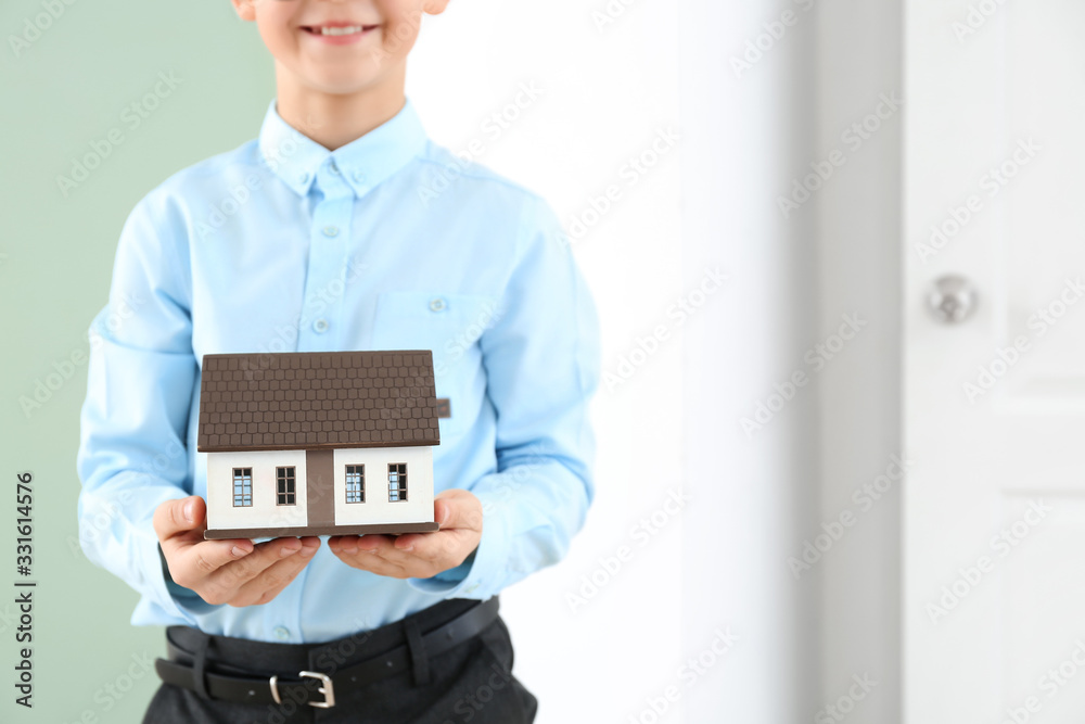 Little real estate agent with model of house indoors Little real estate agent with model of house indoors