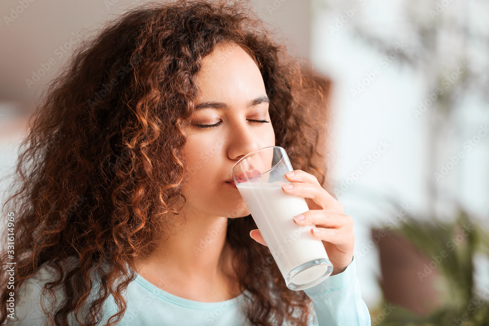Young African-American woman drinking milk in kitchen Young African-American woman drinking milk in kitchen