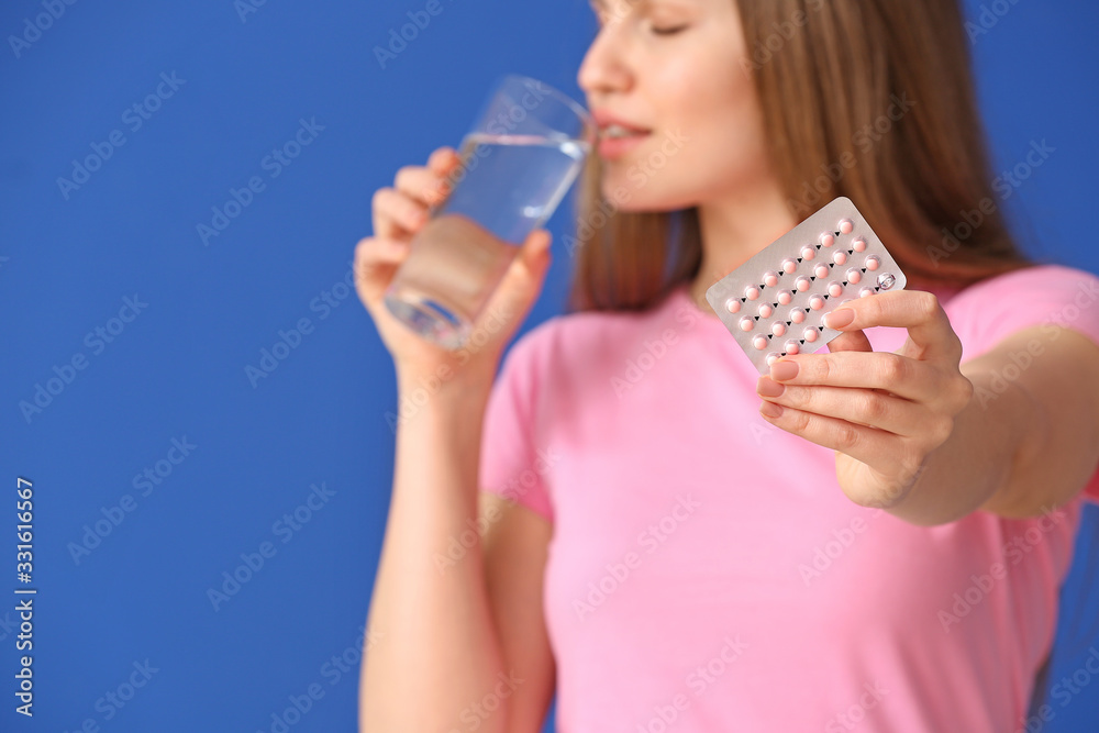 Young woman taking birth control pills on color background Young woman taking birth control pills on color background
