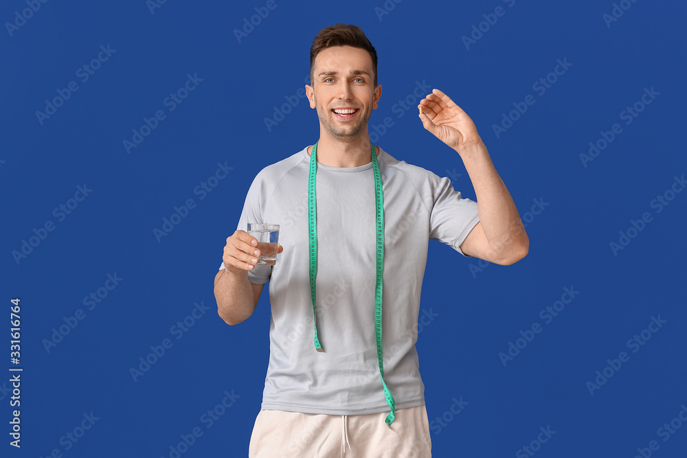 Naklejka premium Young man with weight loss pills and measuring tape on color background