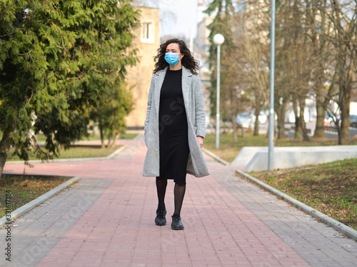 Young beautiful woman walks down the street in a medical mask so as not to get infected Coronaviridae 2019-ncov