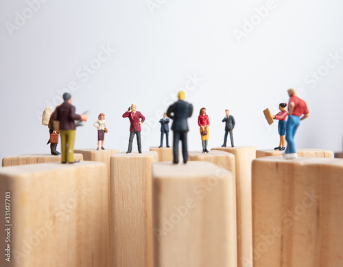 Side view of miniature toys standing on wooden block - social distancing, anti-social or team work concept.