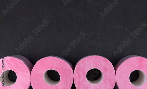 Rolls of pink toilet paper on a dark gray background copy space. Shortage of toilet paper. photo