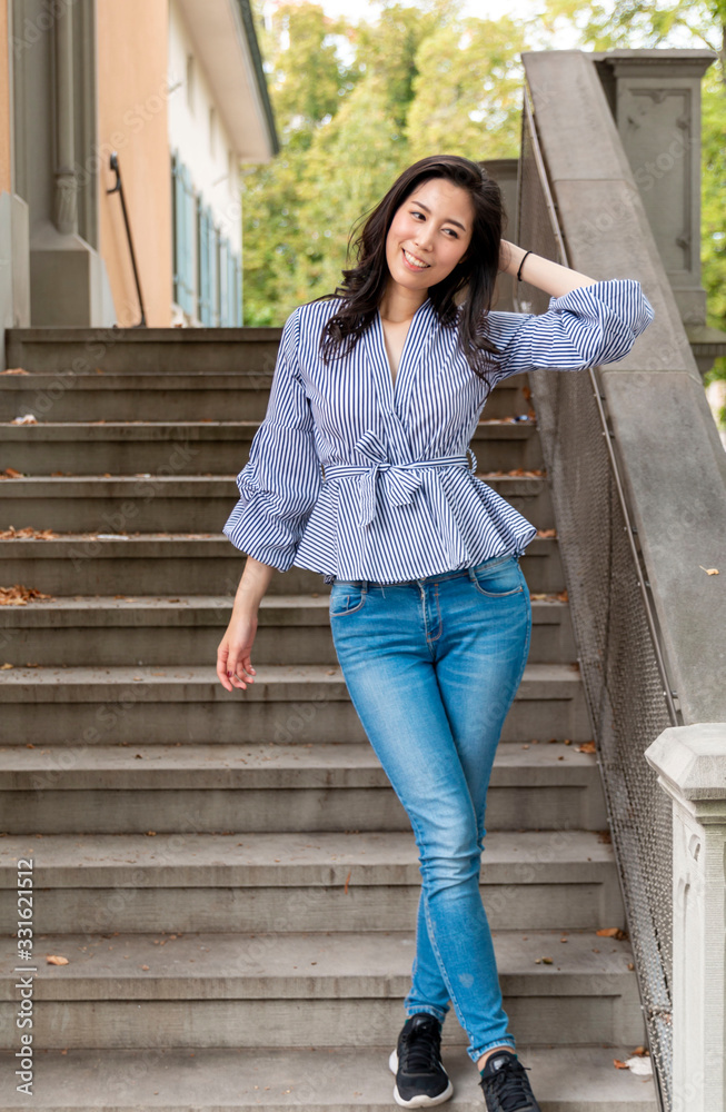 Fototapeta premium Young Asian Girl walking down stairs in Europe city. Europe city woman traveller lifestyle. Travel Europe summer holiday girl enjoying her holiday. Vacation and Holidays in Zurich and Europe concept.