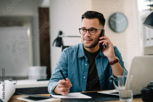 Businessman in office. Handsome man talking on phone at work.	