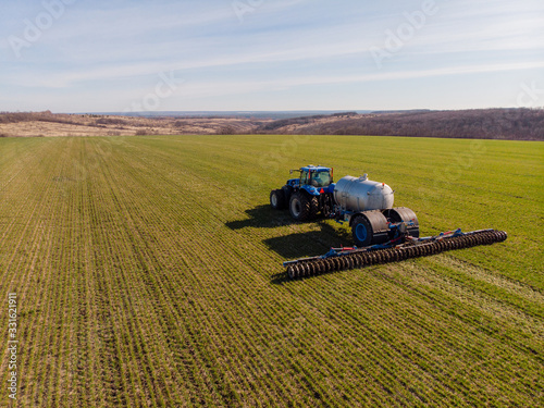 Tractor applying liquid mineral fertilizers to the soil on winter wheat