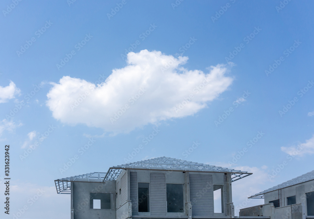 Construction progress in a real estate property project site, people are building the precast house, working in a hot day under cloudy sky, there is a big white clouds flying above the roof