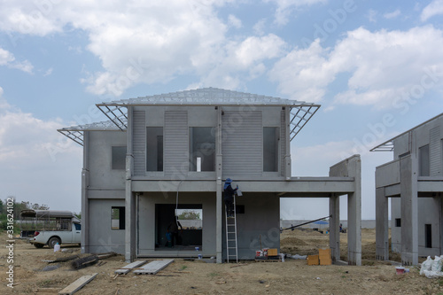 Housing property construction progress, people are building a precast house, the workman working on the stair in a hot day under cloudy sky