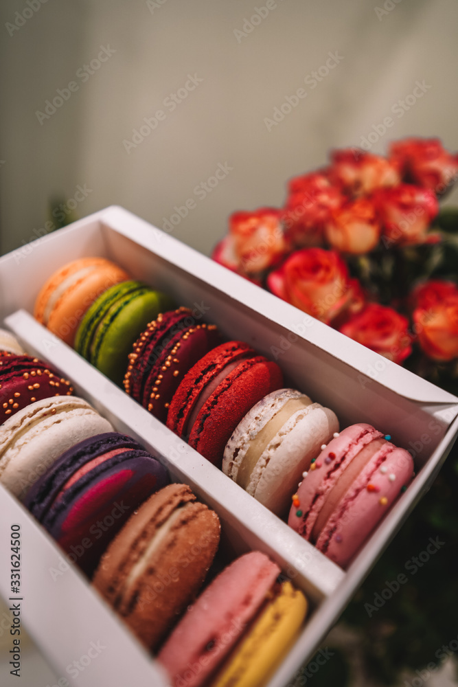 Sweet French dessert of macarons lies on dwarf roses Sweet French dessert of macarons lies on dwarf roses