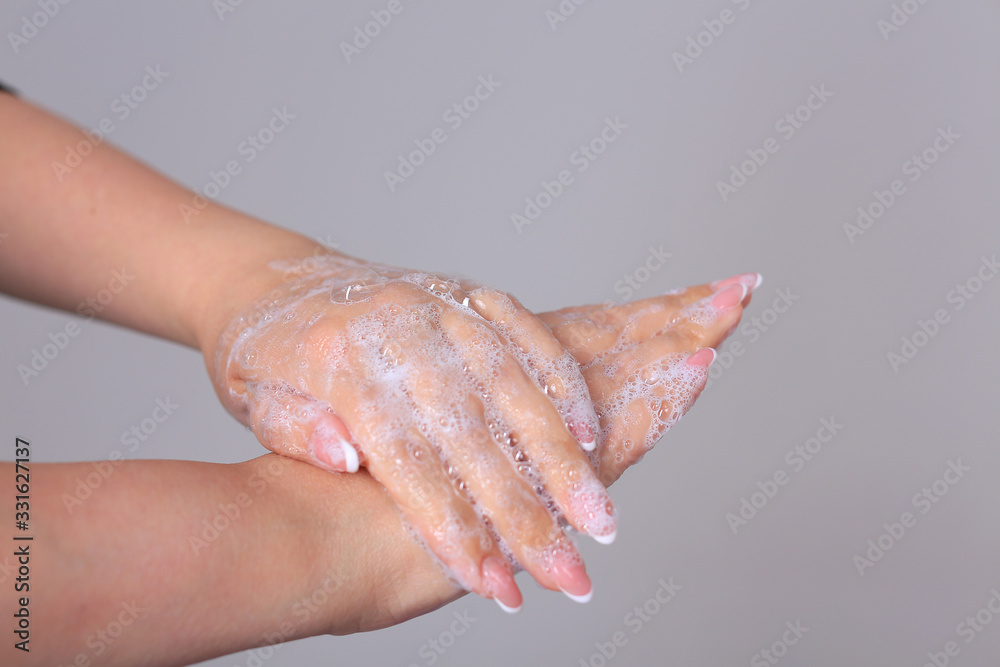 Fototapeta premium Washing female hands with soap on a gray background