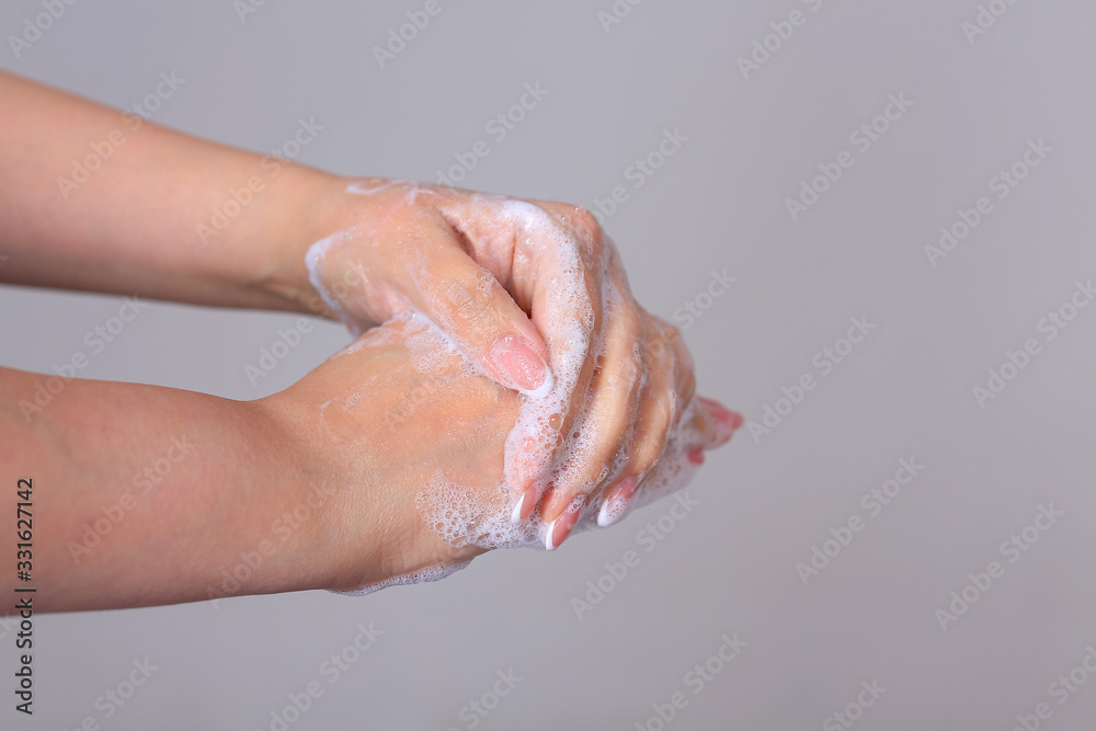 Washing female hands with soap on a gray background Washing female hands with soap on a gray background