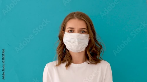 woman putting on surgical mask for corona virus prevention on blue background photo
