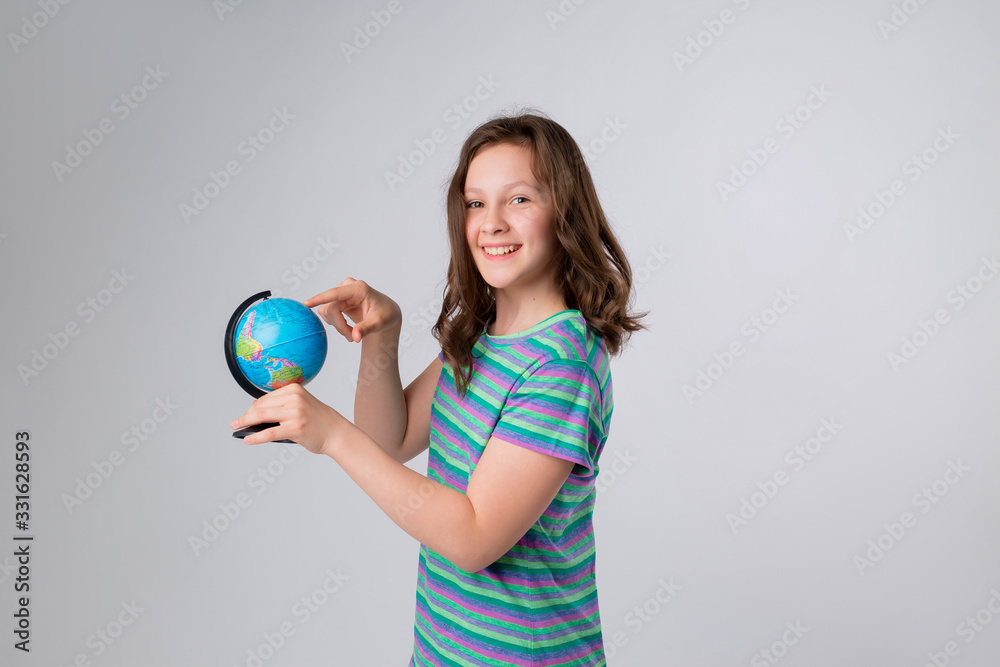 Happy little schoolgirl with globe on her head, standing against white background. Back to school concept. Ideal for banners, registration forms, presentation. Happy little schoolgirl with globe on her head, standing against white background. Back to school concept. Ideal for banners, registration forms, presentation.