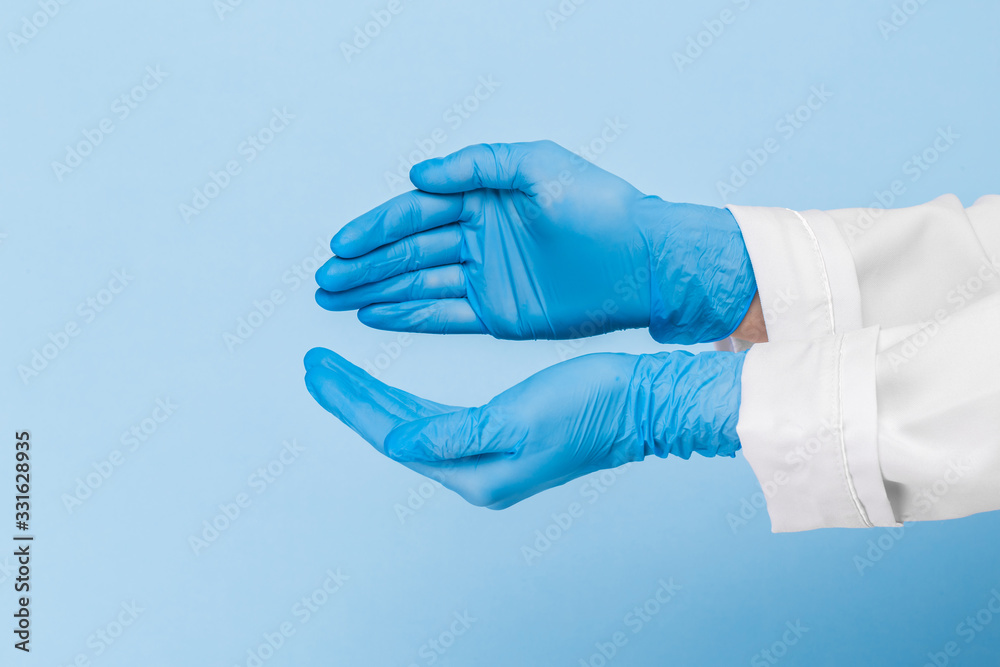 Doctor's hand in a blue medical glove holds an object on a blue background. infection control. mocap, you can insert your product for advertising Doctor's hand in a blue medical glove holds an object on a blue background. infection control. mocap, you can insert your product for advertising
