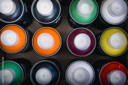 Spray cans with multi-colored paint for street art photographed from above in a box