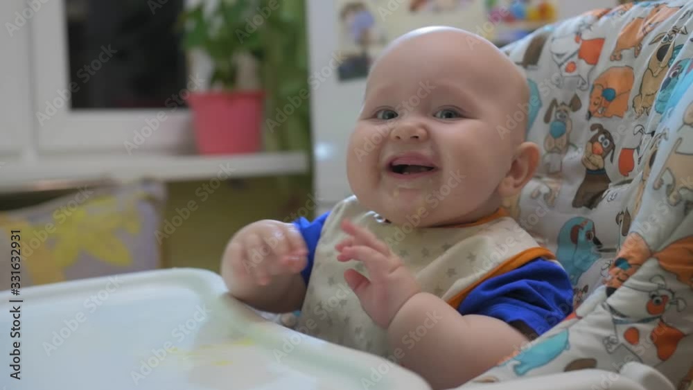 Portrait of 8 month old baby in the kitchen. Little baby sits in highchair Portrait of 8 month old baby in the kitchen. Little baby sits in highchair