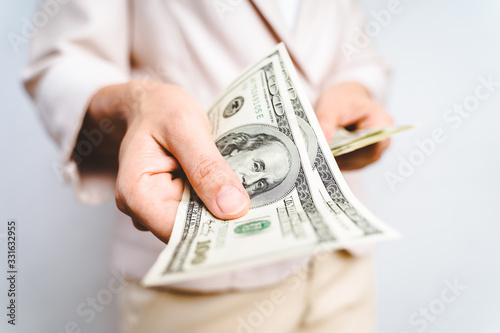 Closeup of business woman hands proposing money us dollar bills on white background. Money Concept.