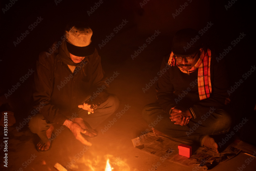 A cheerful Indian Bengali brunette family in winter wear enjoying bonfire  on rooftop in the evening. Indian lifestyle and winter.