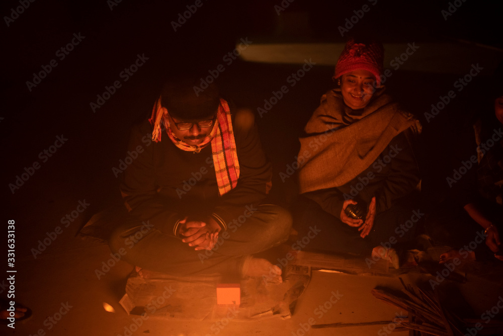 Φωτογραφία A cheerful Indian Bengali brunette family in winter wear enjoying bonfire  on rooftop in the evening
