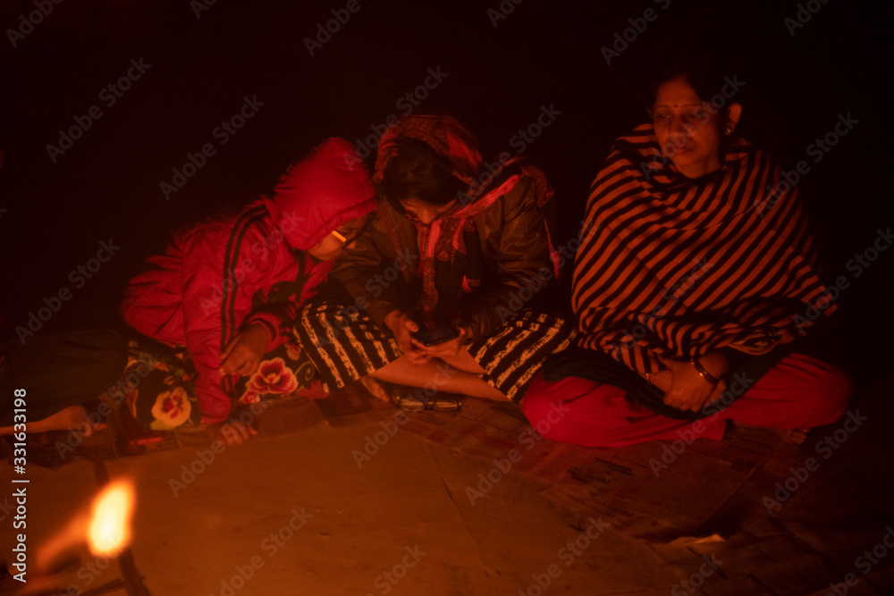 Φωτογραφία A cheerful Indian Bengali brunette family in winter wear enjoying bonfire  on rooftop in the evening