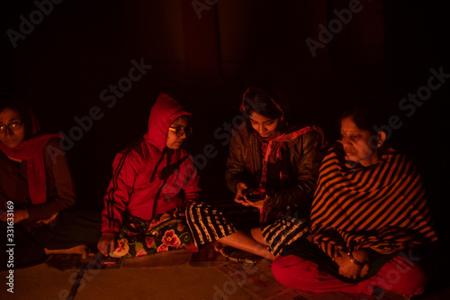 A cheerful Indian Bengali brunette family in winter wear enjoying bonfire on rooftop in the evening. Indian lifestyle and winter.