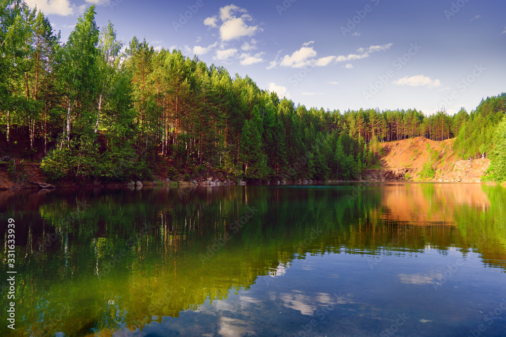 Summer landscape on the shore of a forest lake with clear transparent blue water.