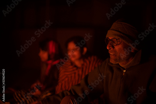 A cheerful Indian Bengali brunette family in winter wear enjoying bonfire on rooftop in the evening. Indian lifestyle and winter.