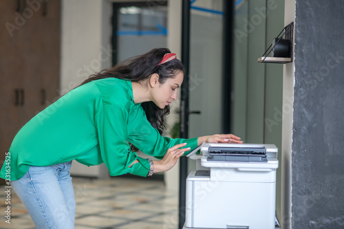 Young woman in jeans bending over a copier.