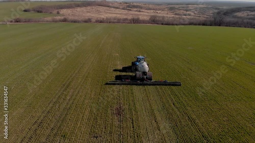 Tractor applying liquid mineral fertilizers to the soil on winter wheat