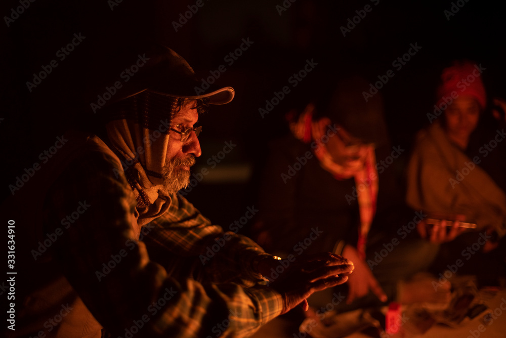 A cheerful Indian Bengali brunette family in winter wear enjoying bonfire  on rooftop in the evening. Indian lifestyle and winter.