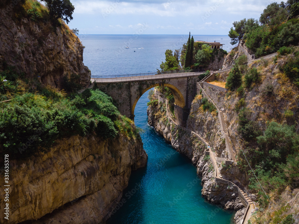 Aerial view of stone bridge and blue sea water. Incredible beauty panorama of a mountains bay. The rocky seashore of southern Italy. Sunny day. Fiordo di furore beach Amalfi coast.