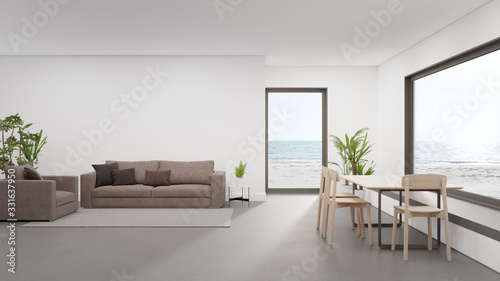 Fototapeta Naklejka Na Ścianę i Meble -  Table on concrete floor of large dining room near living area and sofa in modern beach house or luxury hotel. Minimal home interior 3d rendering with sea view.