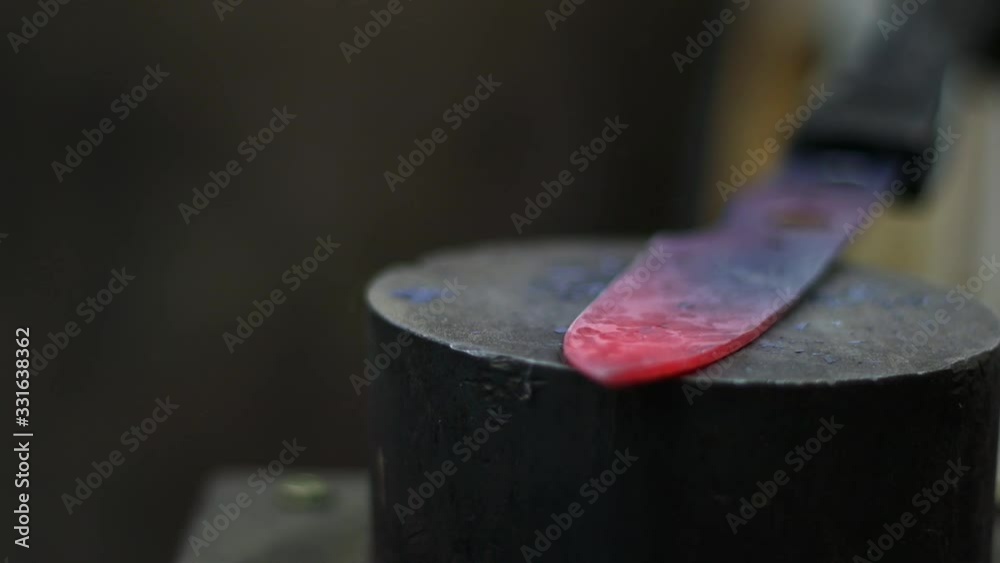 Hammer beating knife during forging process with blured background and hot knife going from burning red to cold black Hammer beating knife during forging process with blured background and hot knife going from burning red to cold black