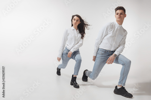 In white. Trendy fashionable couple isolated on white studio background. Caucasian woman and man posing in basic minimal unisex clothes. Concept of relations, fashion, beauty, love. Inclusive. photo