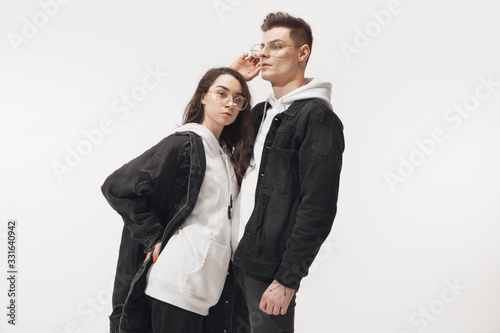 In black. Trendy fashionable couple isolated on white studio background. Caucasian woman and man posing in basic minimal unisex clothes. Concept of relations, fashion, beauty, love. Inclusive. photo