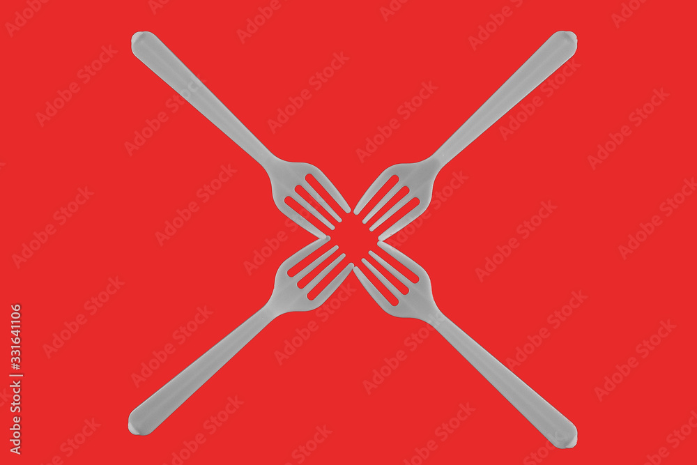four plastic white forks on a red background. isolate. Top view. four plastic white forks on a red background. isolate. Top view.