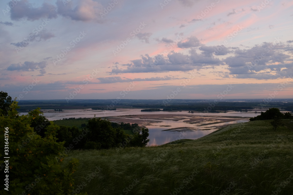 Obraz premium The concept of tourism and solitude with nature. Beautiful pink sunrise on a plain overlooking the river. 