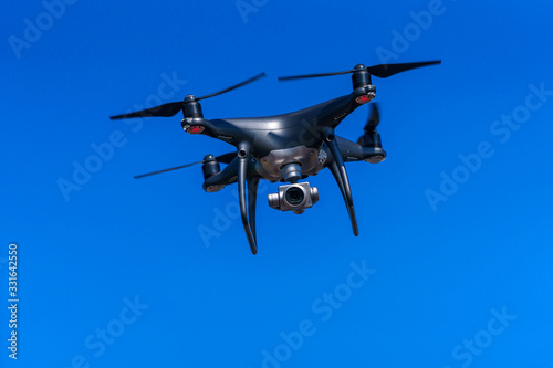 Quadrocopter with a professional camera flies in blue sky. Dron.
