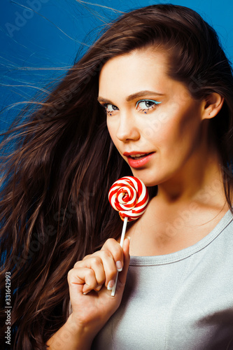 young pretty adorable brunette woman with candy close up posing on blue background  like doll makeup  fashion beauty people concept