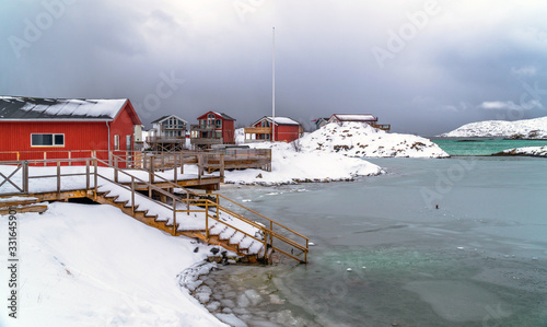 Wooden houses on the banks of the Arctic Ocean in a snowy scenery in Sommarøy near Tromsø, Norway