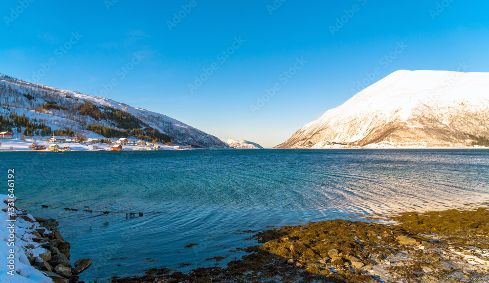 Norway. Fjord at Kvaloya Island with little village on the banks of a fjord in the distance