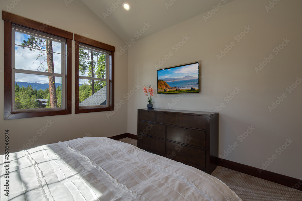 Obraz premium Bright new natural tones bedroom with queen size bed with grey carpet and three windows,