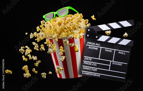 Flying popcorn from striped bucket isolated and 3d glasses on black background