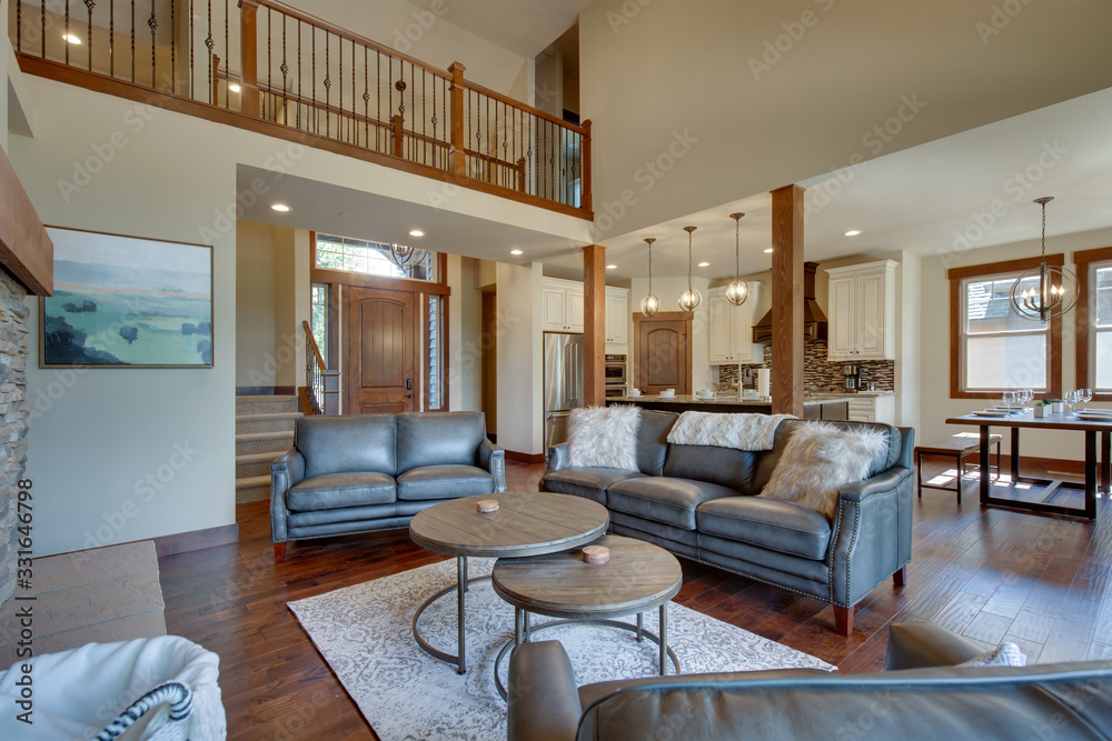 Fototapeta premium An absolute beautiful luxury living room with huge vaulted ceiling, fire place, harwood floor, amazing furniture, and lots of windows and doors.
