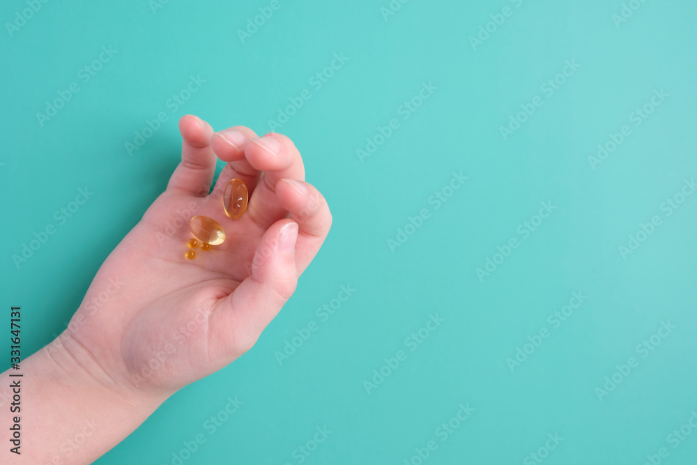 The child's hand holds a dose of vitamins in the hand