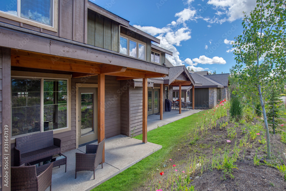 Newly build modern and rustic home from exterior in natural brown and grey colors with walkways, green grass and natural stone.